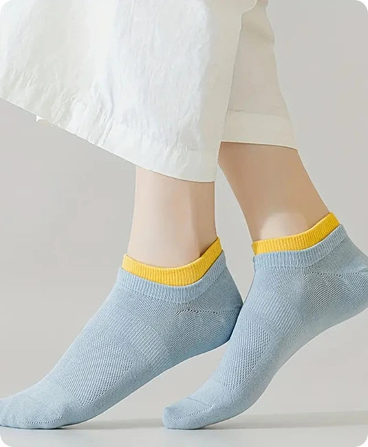 Light blue socks with yellow trim worn by a person on a plain background